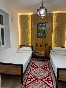 two beds in a room with a red rug at Teskey Hostel Karakol in Karakol