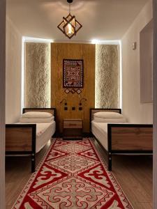 a bedroom with two beds and a rug at Teskey Hostel Karakol in Karakol