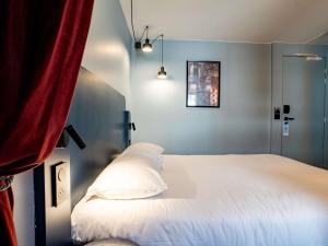a bedroom with a white bed and a red curtain at ibis Styles Bourg-en-Bresse Centre in Bourg-en-Bresse
