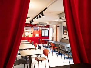 a restaurant with tables and chairs and red curtains at ibis Styles Bourg-en-Bresse Centre in Bourg-en-Bresse