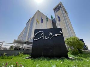 a sign in the grass in front of a building at شير فل in Unayzah
