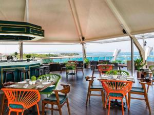 a restaurant with tables and chairs and a view of the ocean at The Kuta Beach Heritage Hotel - Managed by Accor in Kuta
