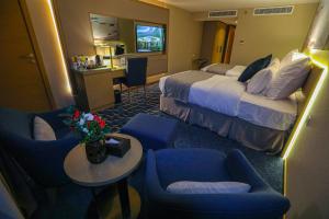 a hotel room with a bed and chairs and a desk at شير فل in Unayzah
