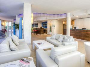 a living room with white couches and a kitchen at Mercure Rimini Lungomare in Rimini