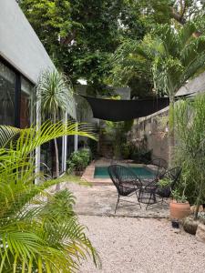 a patio with two chairs and a hammock in a garden at Casa Ramon Merida 2 BR AC Private Pool Centro in Mérida