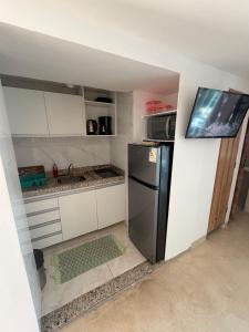 a kitchen with a black refrigerator and white cabinets at Piratas Do Morro Apartamento Praça in Morro de São Paulo