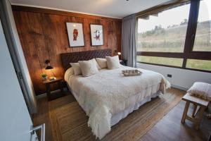 a bedroom with a large bed and a large window at Private Terrace with Wellness Studio & Fireplace in Puerto Varas