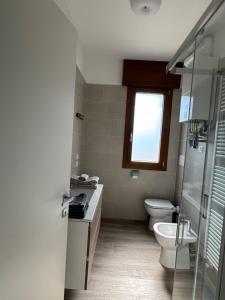 a bathroom with a toilet and a sink and a window at Tarvisium Apartment in Treviso