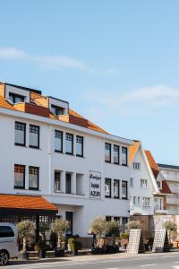 a white building with a white van parked in front of it at Boutique Hotel Azur in De Haan