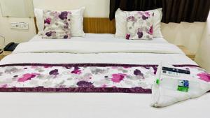 a bed with pink and white sheets and pillows at Hotel cressida green palace - near redisson squar in Indore
