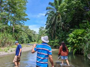 a group of three people crossing a river at Casa Chilamate in Puerto Jiménez