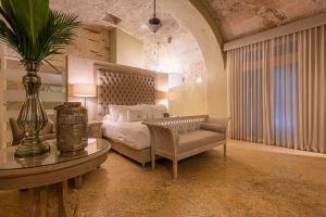 a bedroom with a bed and a table and a couch at Hotel Casa del Gobernador in Cartagena de Indias +85 photos