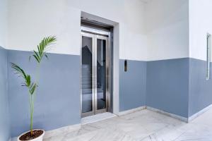 a blue and white room with a door and a plant at Hotel O DLF Phase 1 Metro Station Gurugram in Gurgaon