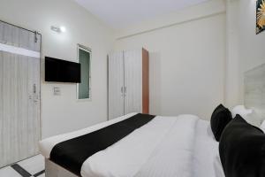 a white bedroom with a bed and a tv on the wall at Hotel O DLF Phase 1 Metro Station Gurugram in Gurgaon