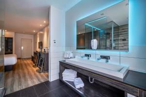 a bathroom with a sink and a large mirror at Hôtel Ô Laval in Laval