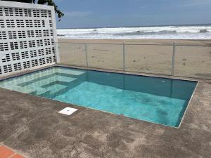 a swimming pool next to a beach with the ocean at Front Beach Beautiful house with pool & AC in Pochomil