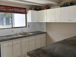 a kitchen with white cabinets and a sink and a window at Front Beach Beautiful house with pool & AC in Pochomil
