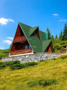 a log cabin with a green roof on a hill at Komovi Sky House in Andrijevica