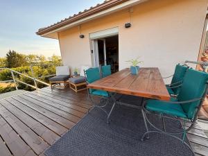 a wooden table and chairs on a deck at Le Refuge des Vignes in Sainte-Colombe