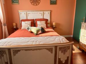 a bedroom with a bed with orange and green walls at Le Refuge des Vignes in Sainte-Colombe