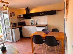 a kitchen with a wooden table and black chairs at Le Refuge des Vignes in Sainte-Colombe +17 photos