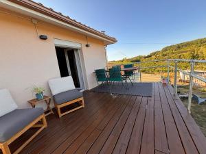 a wooden deck with chairs and a table on it at Le Refuge des Vignes in Sainte-Colombe