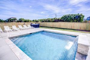 a swimming pool in a yard with chairs and a fence at 4059 - Bikinis Martinis in Kitty Hawk