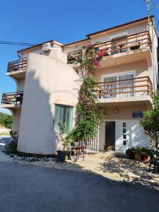 a large white building with a balcony and plants at Apartmani Svitlana in Sukošan