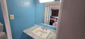 a blue bathroom with a sink and a mirror at Lamplighter Inn Independence in Independence