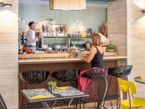 a man and a woman preparing food in a kitchen at Aparthotel Adagio Rome Vatican in Rome