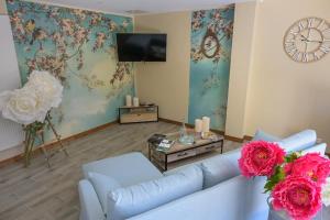 a living room with a couch and flowers and a clock at Rouges-Gorges 