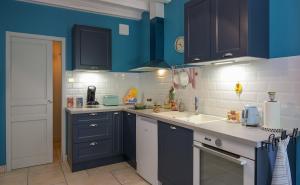 a kitchen with blue cabinets and white counter tops at Rouges-Gorges 