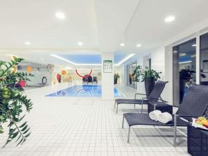 a lobby with a swimming pool and chairs in a building at Mercure Düsseldorf Kaarst in Kaarst