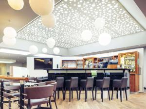 a restaurant with a bar with chairs and lights at Mercure Düsseldorf Kaarst in Kaarst