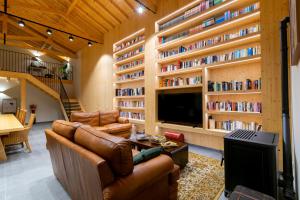 a living room with a couch and a tv and book shelves at Eira das Maçãs - Óbidos 