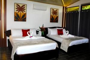 two beds in a hotel room with bows on them at Pino Lodge, Río Celeste in Bijagua