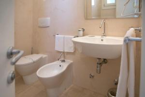a white bathroom with a sink and a toilet at Antica Masseria Ficazzana - Tenuta in Marina di Pescoluse