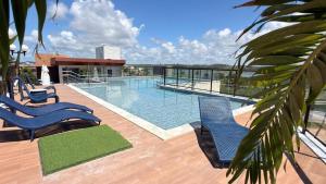 a swimming pool with two blue chairs on a deck at Porto Atlantis by You In | 80m from Porto de Galinhas Beach in Porto De Galinhas