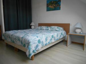 a bedroom with a bed with a blue and white comforter at Angenehmes Haus in Perros-Guirec