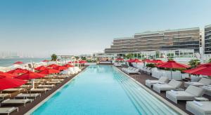 a swimming pool with umbrellas and chairs and a hotel at Th8 Palm Dubai Beach Resort, Vignette Collection by IHG in Dubai