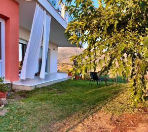 a porch of a house with a chair on the grass at Horizon House, with Olive Grove and a small Vineyard in Amarynthos