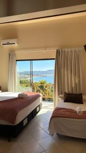 a bedroom with two beds and a large window at Pousada Aquarela de Bombinhas in Bombinhas +283 photos
