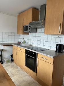 a kitchen with wooden cabinets and a black oven at Ruhig gelegene Ferienwohnung in Waldbrunn