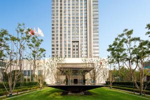 a large tall building with a fountain in a park at HUALUXE Shanghai Changfeng Park by IHG in Shanghai