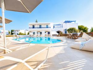 a swimming pool in a resort with chairs and tables at Anna Studios in Agios Prokopios
