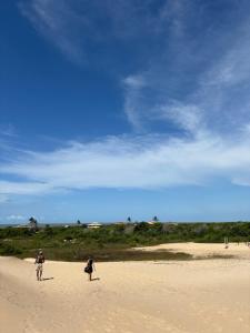 two people standing on a beach flying a kite at Aroeira Suite in Conceição da Barra