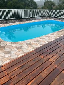 a swimming pool with a wooden deck next to it at Pesqueiro Restaurante e Pousada Pingo de Ouro in Piedade