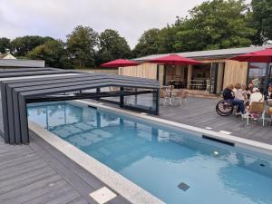 a swimming pool with a deck and a restaurant at Aurorabelle Lodge in Brixham
