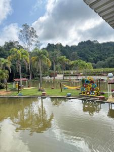 a park with a pool of water with a playground at Pesqueiro Restaurante e Pousada Pingo de Ouro in Piedade