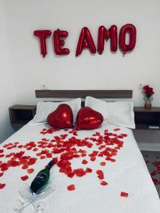 a bed with red roses on it with a bottle of alcohol at Pesqueiro Restaurante e Pousada Pingo de Ouro in Piedade